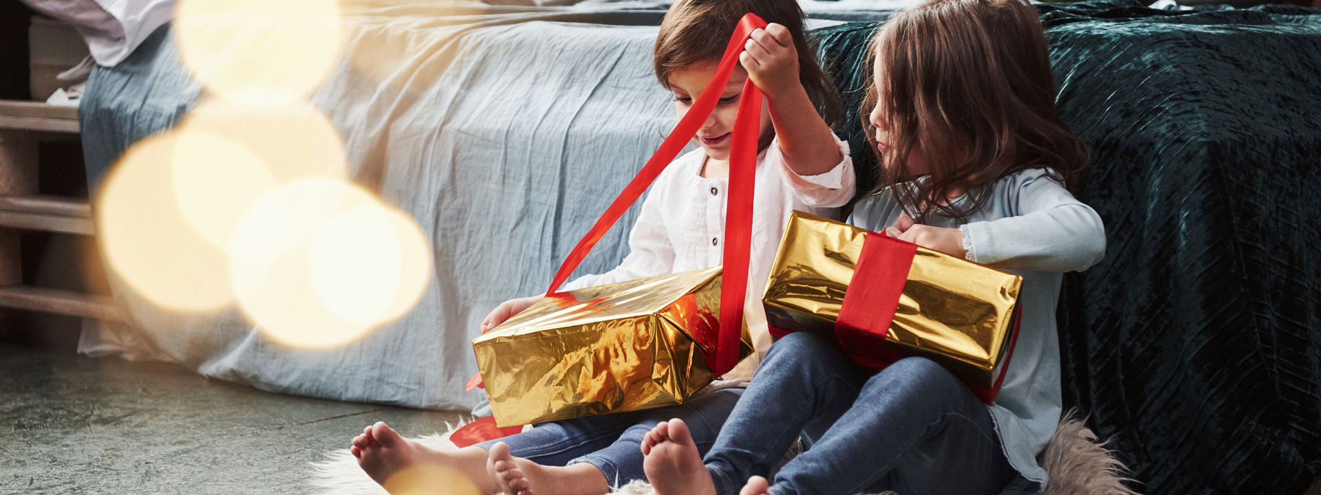 Kinder packen in weihnachtlichem Ambiente Geschenke aus